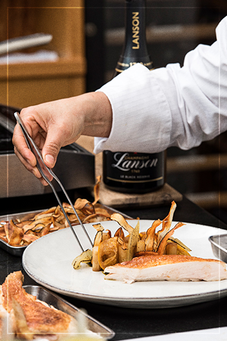 Image de la Cheffe Beatriz Gonzalez en train de préparer l'assiette de Suprême de Volaille croustillant acoompagné de Black Reserve Lanson | Champagne Lanson