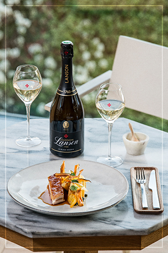 Image d'ambiance de l'assiette de Suprême de Volaille croustillant acoompagné de Black Reserve Lanson sur une table en marbre et ses verres de champagne | Champagne Lanson