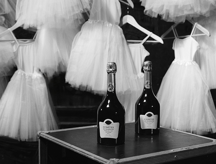 Deux bouteilles Comtes de Champagne Taittinger dans une salle de danse classique avec des danseuses
